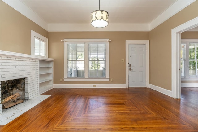 unfurnished living room featuring dark parquet floors, built in features, ornamental molding, and a brick fireplace