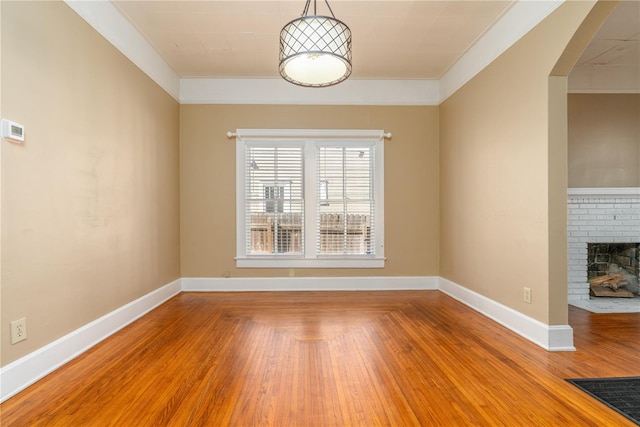 spare room featuring hardwood / wood-style flooring, a fireplace, and crown molding