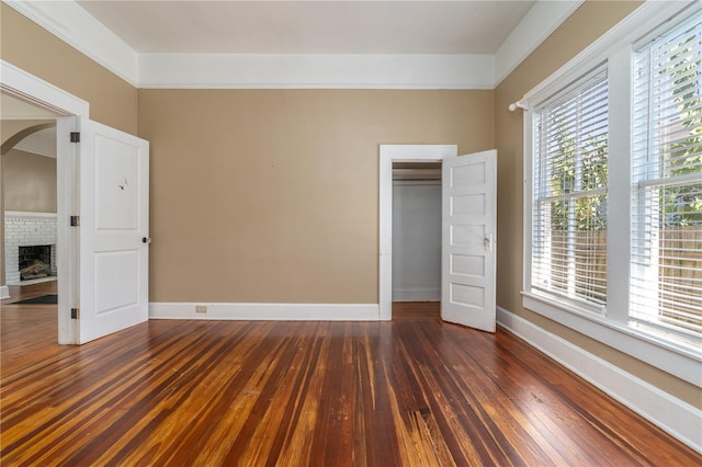 unfurnished bedroom with a fireplace, a closet, and dark hardwood / wood-style flooring