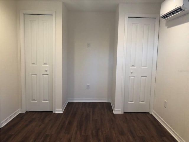 unfurnished bedroom featuring a wall mounted air conditioner and dark wood-type flooring