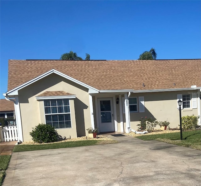 ranch-style house with roof with shingles and stucco siding