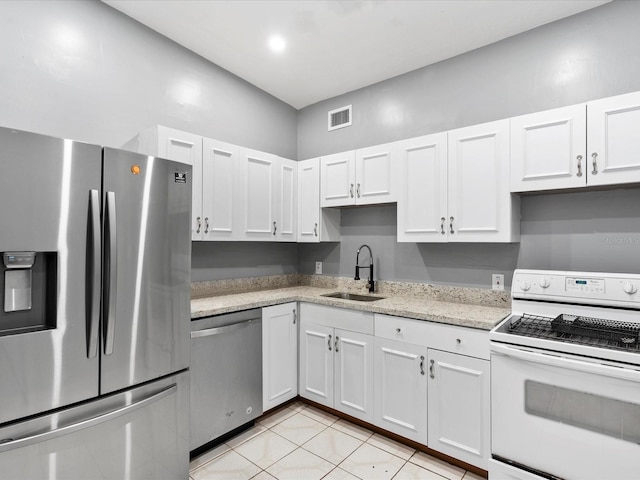 kitchen with sink, light stone counters, light tile patterned floors, stainless steel appliances, and white cabinets