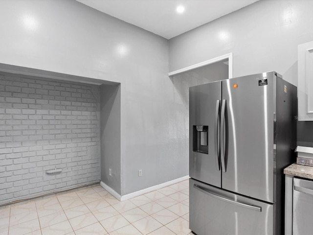 kitchen with brick wall, appliances with stainless steel finishes, and light tile patterned floors