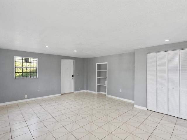 empty room featuring a textured ceiling and built in shelves