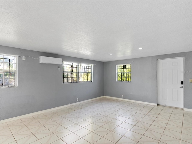 unfurnished room with a textured ceiling and an AC wall unit