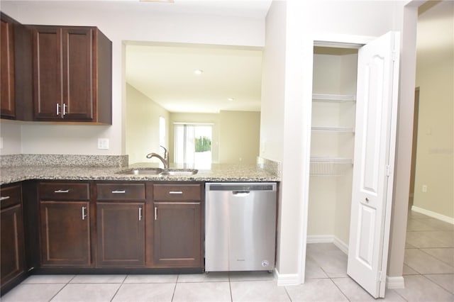 kitchen with light stone countertops, sink, light tile patterned floors, and stainless steel dishwasher