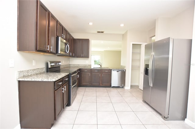 kitchen with dark brown cabinetry, light stone countertops, sink, and appliances with stainless steel finishes