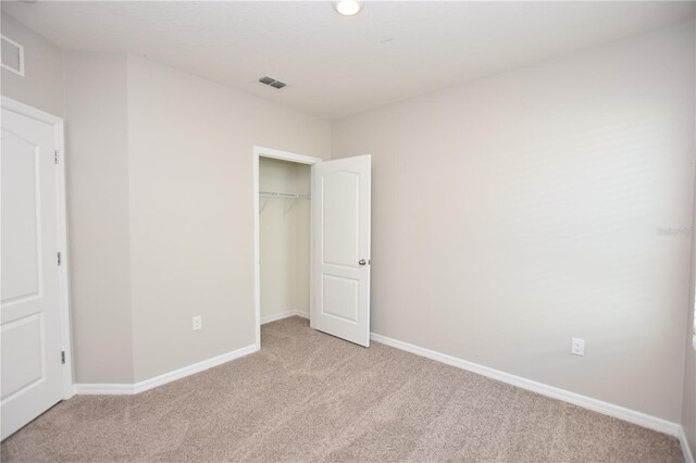 unfurnished bedroom featuring light carpet and a closet