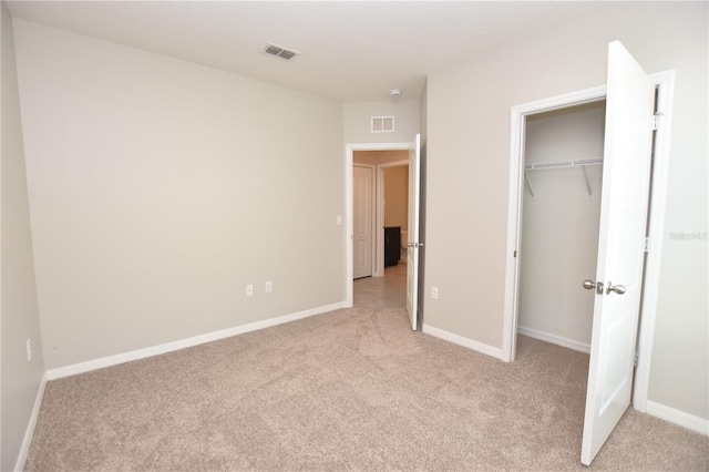 unfurnished bedroom featuring light carpet and a closet