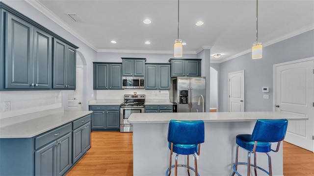 kitchen featuring a kitchen island with sink, pendant lighting, light hardwood / wood-style floors, and appliances with stainless steel finishes