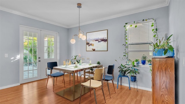 dining space with french doors, ornamental molding, and light wood-type flooring