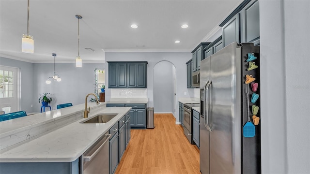 kitchen with pendant lighting, sink, crown molding, appliances with stainless steel finishes, and a center island with sink