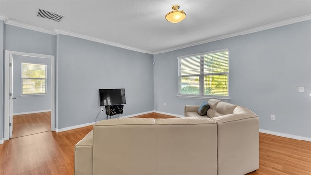 living room with ornamental molding, a healthy amount of sunlight, and light wood-type flooring