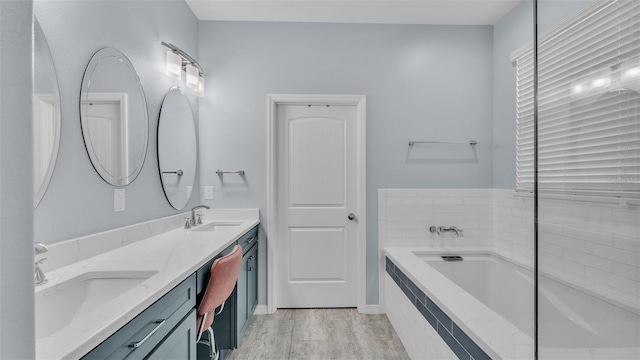 bathroom with vanity, wood-type flooring, and tiled bath