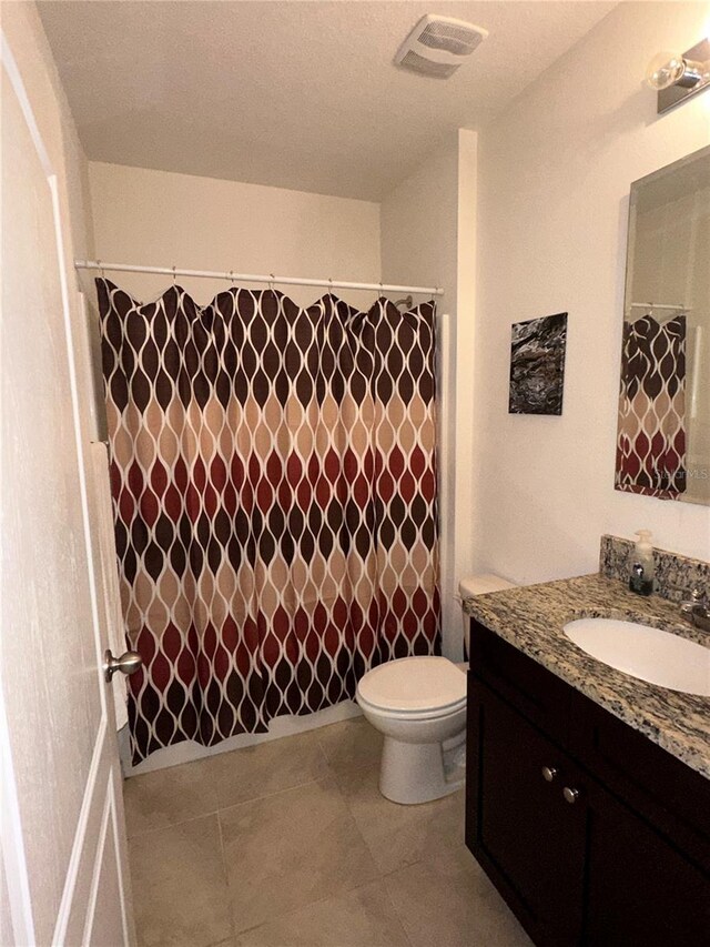 bathroom with toilet, vanity, tile patterned floors, and walk in shower