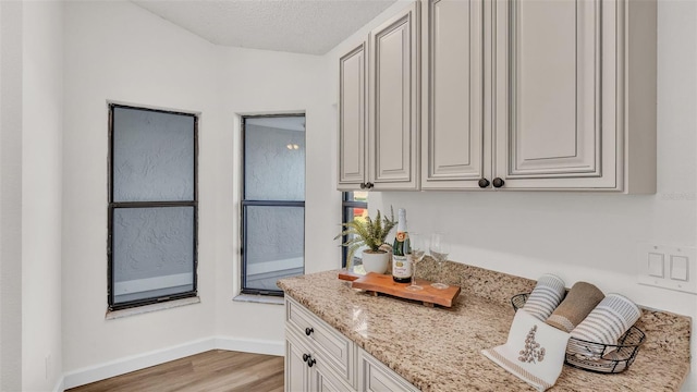 kitchen featuring white cabinets, light stone counters, light wood-type flooring, and a textured ceiling