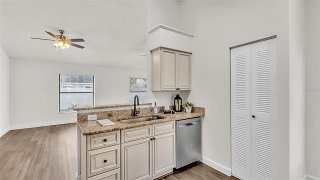 kitchen with dishwasher, sink, hardwood / wood-style floors, and light stone counters