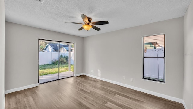 unfurnished room with a healthy amount of sunlight, a textured ceiling, and light wood-type flooring