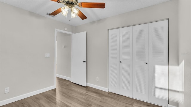 unfurnished bedroom with ceiling fan, a closet, light hardwood / wood-style floors, and a textured ceiling