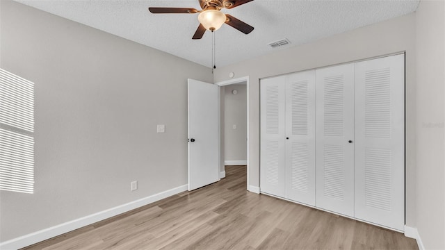 unfurnished bedroom with a textured ceiling, a closet, light hardwood / wood-style floors, and ceiling fan