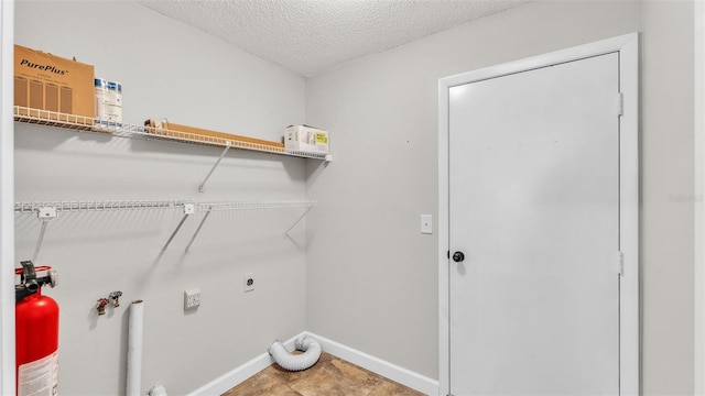 laundry area with electric dryer hookup and a textured ceiling