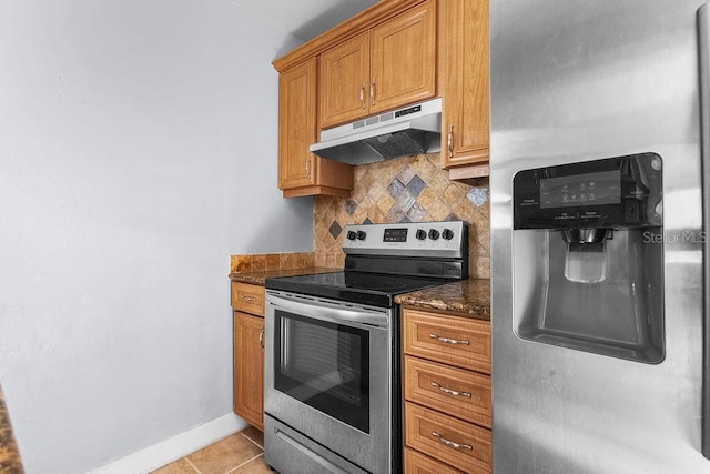 kitchen with light tile patterned floors, stainless steel appliances, tasteful backsplash, and dark stone countertops