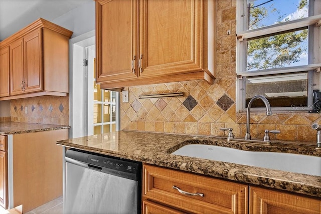 kitchen featuring decorative backsplash, stainless steel dishwasher, dark stone countertops, and sink