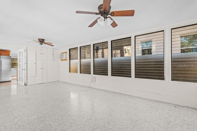 unfurnished sunroom with an AC wall unit and ceiling fan