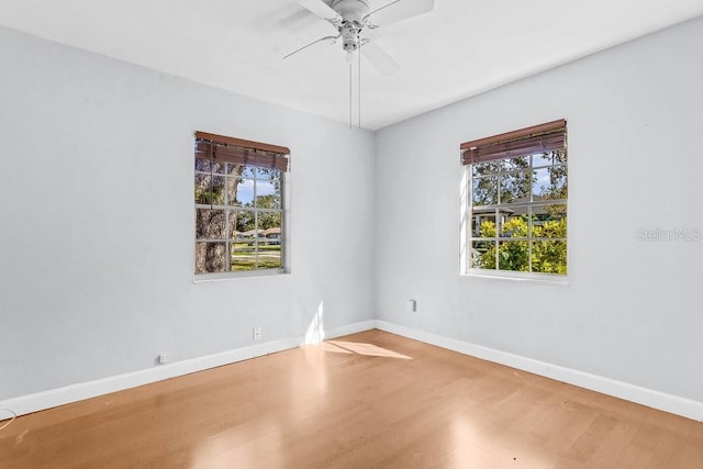 empty room featuring ceiling fan, a healthy amount of sunlight, and wood-type flooring