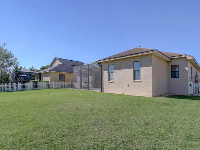 back of property with glass enclosure and a yard