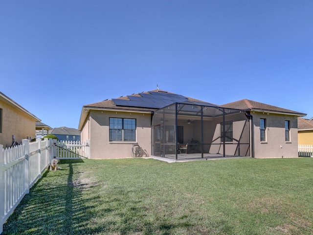 back of house featuring solar panels, a yard, glass enclosure, and a patio area