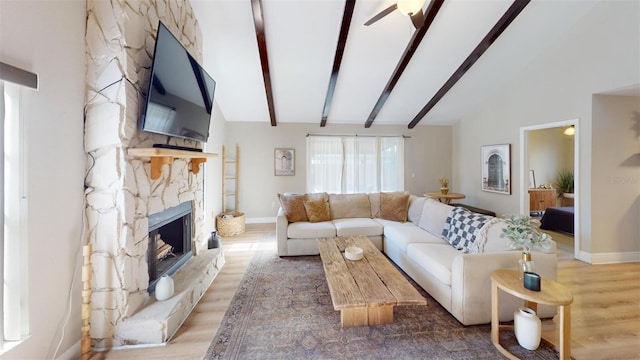 living room with beam ceiling, a stone fireplace, high vaulted ceiling, and wood-type flooring