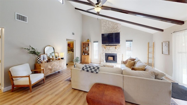 living room featuring a wealth of natural light, a fireplace, beamed ceiling, and light hardwood / wood-style floors