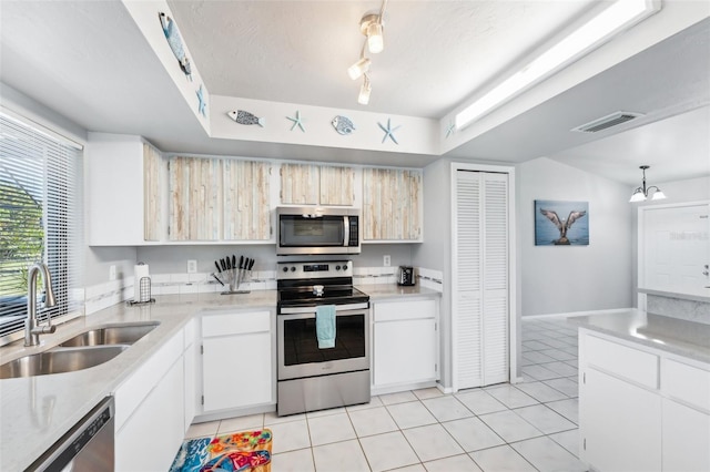 kitchen featuring white cabinetry, sink, hanging light fixtures, light tile patterned flooring, and appliances with stainless steel finishes