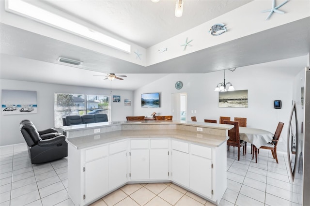 kitchen with white cabinets, ceiling fan with notable chandelier, stainless steel fridge, and light tile patterned flooring