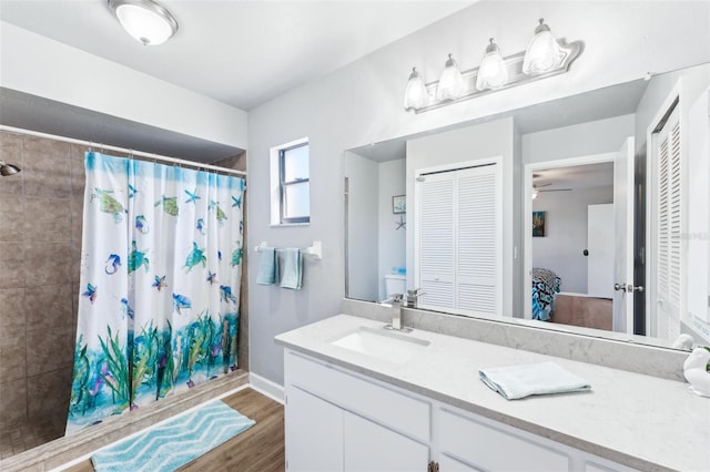 bathroom featuring ceiling fan, vanity, wood-type flooring, and walk in shower