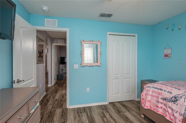 bedroom with dark hardwood / wood-style flooring and a closet