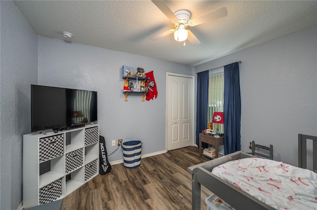 bedroom with a textured ceiling, a closet, dark hardwood / wood-style floors, and ceiling fan