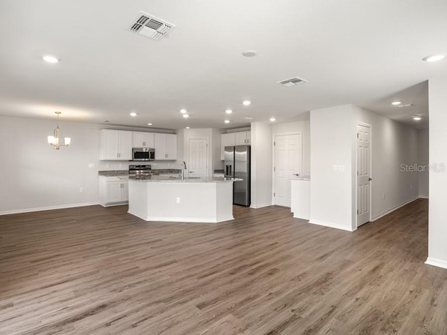 kitchen featuring dark hardwood / wood-style floors, white cabinetry, stainless steel appliances, and a kitchen island with sink