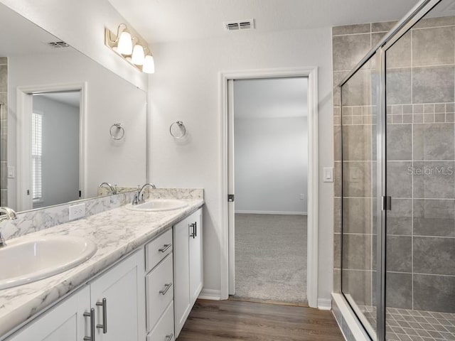 bathroom featuring vanity, wood-type flooring, and a shower with door