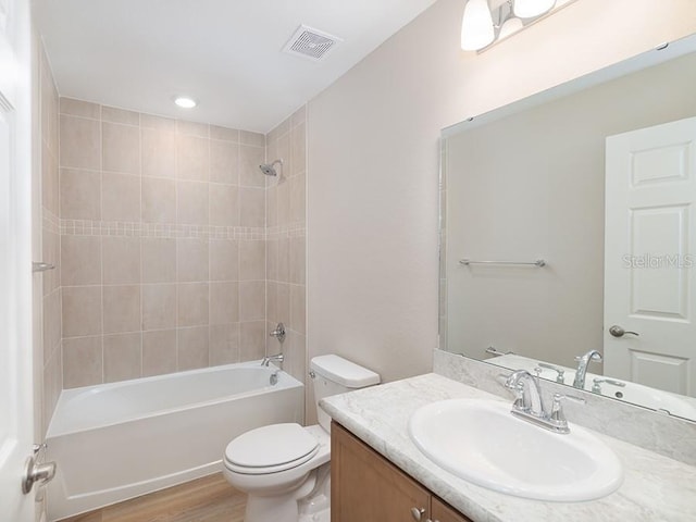 full bathroom with hardwood / wood-style flooring, vanity, toilet, and tiled shower / bath combo