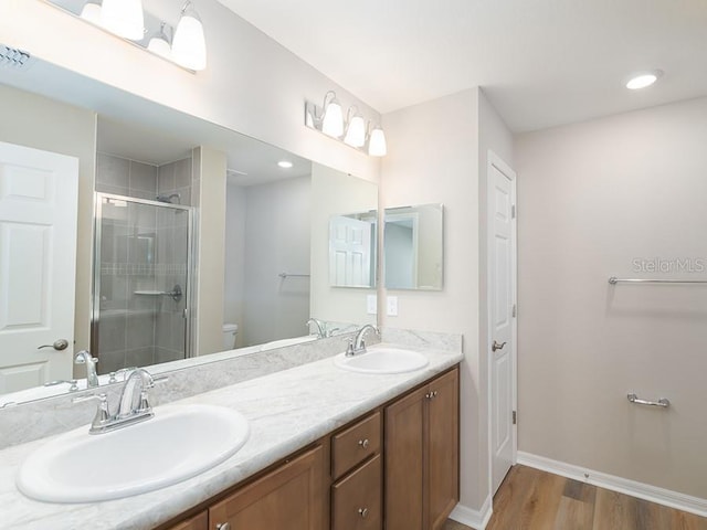 bathroom featuring wood-type flooring, toilet, an enclosed shower, and vanity