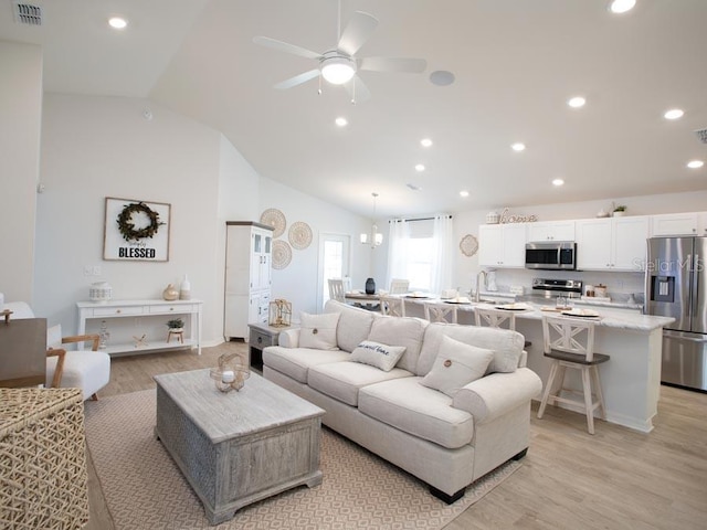 living room with ceiling fan, light wood-type flooring, and lofted ceiling