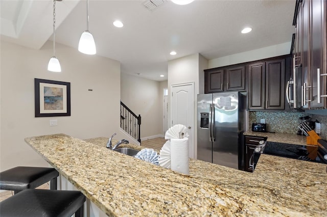 kitchen with dark brown cabinetry, sink, kitchen peninsula, stainless steel fridge, and decorative backsplash