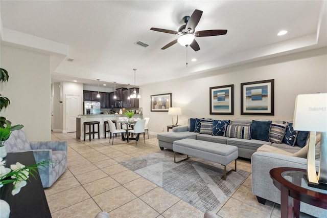 tiled living room with ceiling fan with notable chandelier