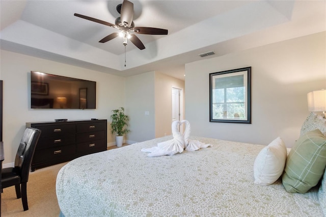 carpeted bedroom featuring ceiling fan and a raised ceiling