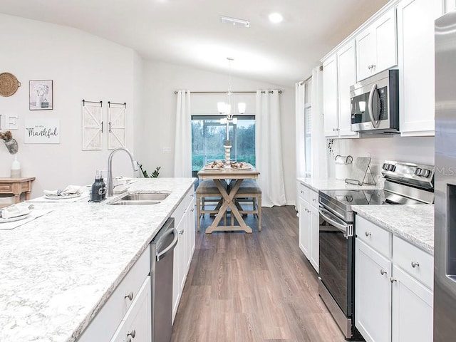 kitchen featuring hardwood / wood-style floors, lofted ceiling, white cabinets, sink, and stainless steel appliances