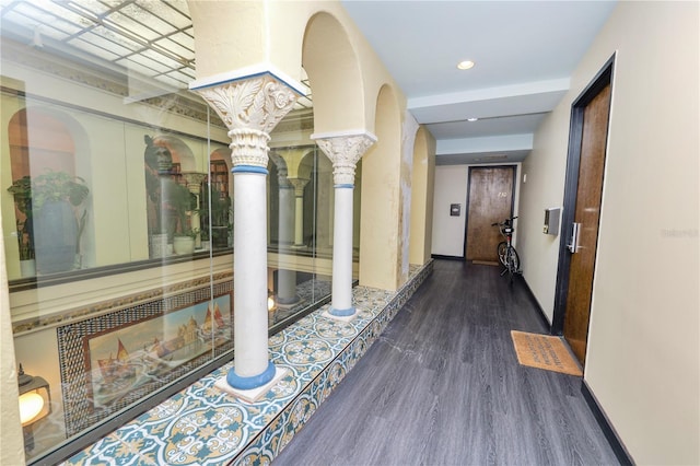 hallway with ornate columns and dark wood-type flooring