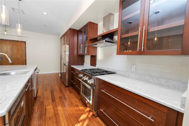 405 Central Ave Unit 210, Saint Petersburg, FL 33701 - kitchen featuring appliances with stainless steel finishes, a sink, wall chimney exhaust hood, dark wood-style floors, and pendant lighting