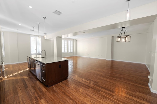 kitchen with a center island with sink, hanging light fixtures, dark wood-type flooring, and sink